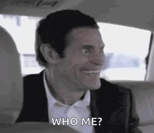 a man in a suit is sitting in the back seat of a car .