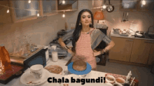 a woman standing in a kitchen with a cake on a plate and the words ' chala bagundi ' on the bottom right