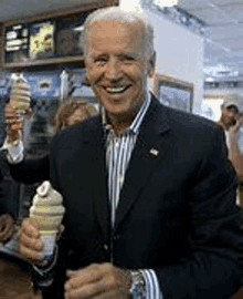 a man in a suit is holding a ice cream cone and smiling .