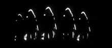 a black and white photo of a group of people standing in front of a stage with lights behind them .