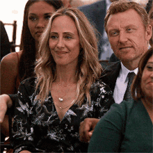 a man in a suit and tie is sitting next to a woman in a black and white floral dress .