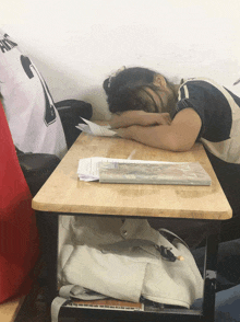 a girl sleeping on a desk with a shirt that says hong on it