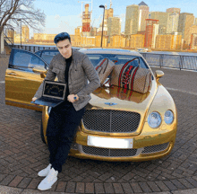 a man stands in front of a gold bentley car