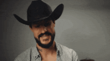 a man with a beard is wearing a black cowboy hat