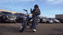 a man sits on a blue motorcycle in a parking lot with a license plate that says ' n00016 ' on it