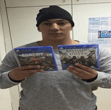 a man is holding two playstation 4 games in his hands one of which is far cry 4