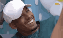 a man wearing a white baseball cap is smiling .