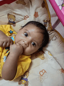 a baby wearing a yellow shirt that says city lays on a blanket