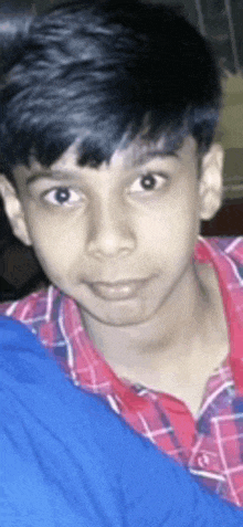 a young boy wearing a red and white plaid shirt