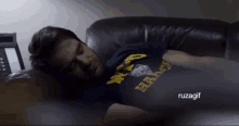 a man laying on a couch wearing a shirt that says ' hard ' on it