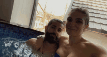 a man and a woman are posing for a photo in a pool