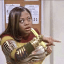 a woman is pointing at something while holding a banana in her hand .