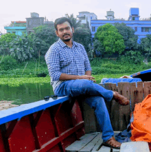 a man in a plaid shirt sits on the edge of a boat