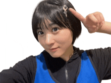 a girl wearing a black shirt and a blue vest is pointing up