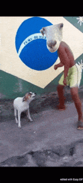 a man standing next to a dog with a sheep head on his head in front of a brazilian flag