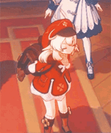 a girl in a red jacket and hat is standing on a red carpet .