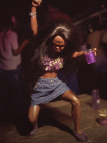 a barbie doll is holding a purple cup