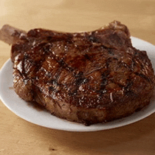 a steak on a white plate on a table