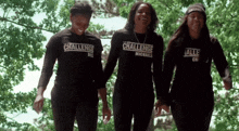 three women wearing the challenge shirts are holding hands and smiling