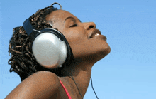 a woman wearing headphones with her eyes closed is smiling