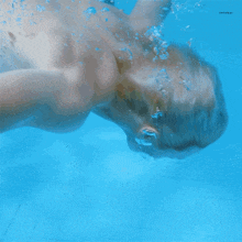 a shirtless man is swimming underwater in a pool with a watermark that says ' sntrokai ' on it