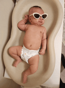 a baby wearing sunglasses and a diaper is laying on a changing mat