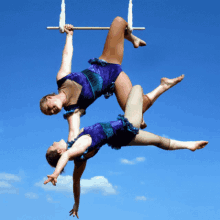 two women are performing aerial acrobatics on a trapeze