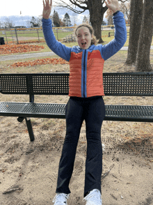 a girl sitting on a bench with her arms up