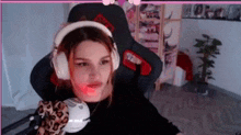 a woman wearing headphones and a mask is sitting in a chair in a room .