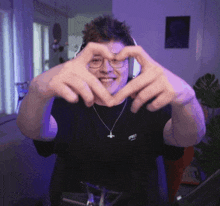 a man making a heart shape with his hands while wearing headphones and a shirt that says ' spec ' on it