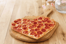 a heart shaped pepperoni pizza sitting on a wooden cutting board