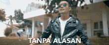 a man wearing sunglasses and a leather jacket is standing in front of a house with the words tanpa alasan written on the bottom