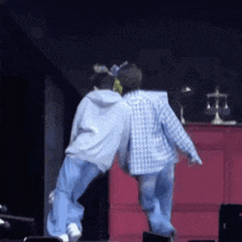 two men are standing next to each other on a stage and dancing .