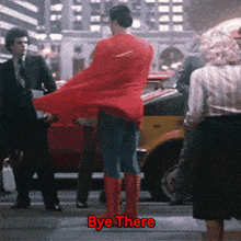 a man in a superman costume is standing on a street with the words bye there below him