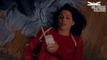 a woman in a red sweater is laying on the floor holding a remote control with gilmore girls written on the bottom