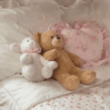 a brown teddy bear and a white teddy bear sit on a bed