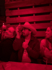 a man in a cowboy hat sits at a table with other people