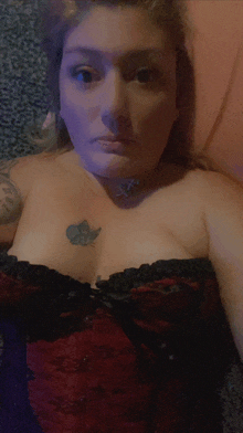 a woman with a butterfly tattoo on her chest is wearing a red and black corset