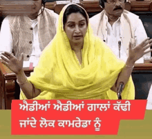 a woman in a yellow dress is sitting in front of a microphone in a parliament .