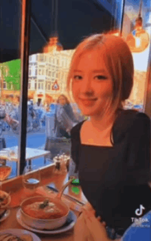 a woman is sitting at a table in a restaurant with a bowl of soup on it .