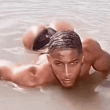 a shirtless man is swimming in the water with his back to the camera .