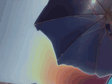 a blue umbrella against a blue sky with a sunset in the background