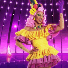 a drag queen is wearing a yellow and pink dress and a hat with fruit on it .