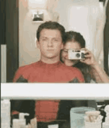 a man and a woman are taking a selfie in the bathroom mirror .