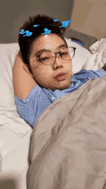 a young man wearing glasses is laying in bed