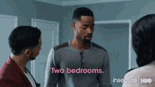 two men and a woman are standing in a room and one of them is saying two bedrooms .