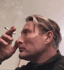 a man is smoking a cigarette in a room .