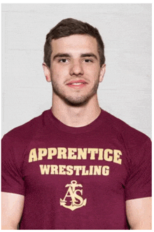 a man is wearing a maroon apprentice wrestling t-shirt