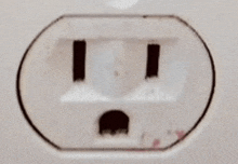 a close up of a white electrical outlet with a black hole in it