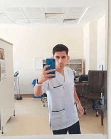 a man taking a selfie in front of a mirror with a calendar on the wall behind him